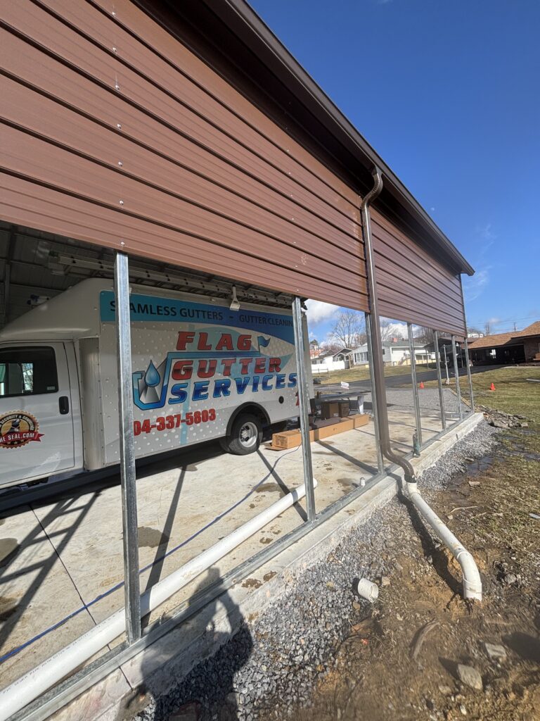 Flag Gutter Services Cleaning Gutters And Installing Seamless Gutters On A Building With Equipment Parked Nearby